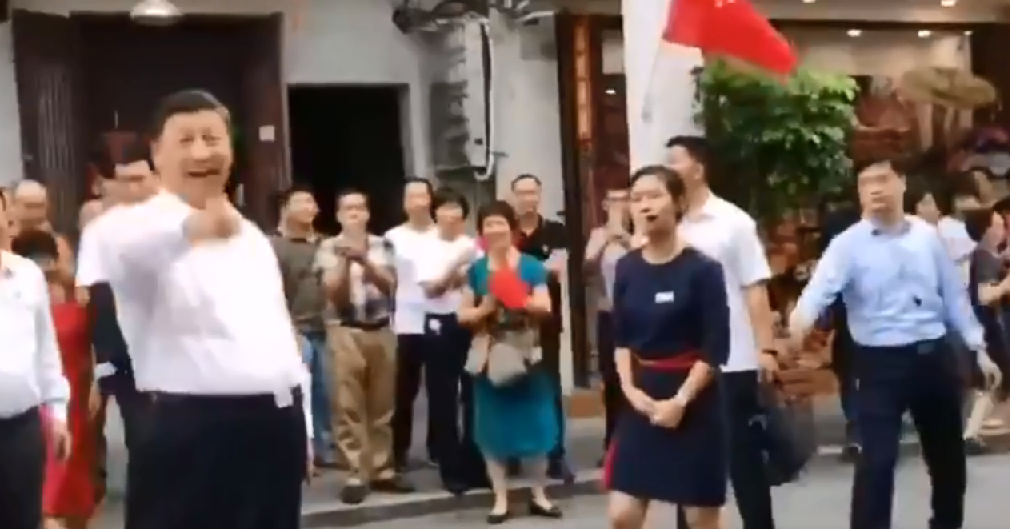 一名身著深藍色洋裝的女導遊可能離習近平太近了，一名淺藍衣安全人員因此出手試圖將女導遊拉回。(影像截圖)