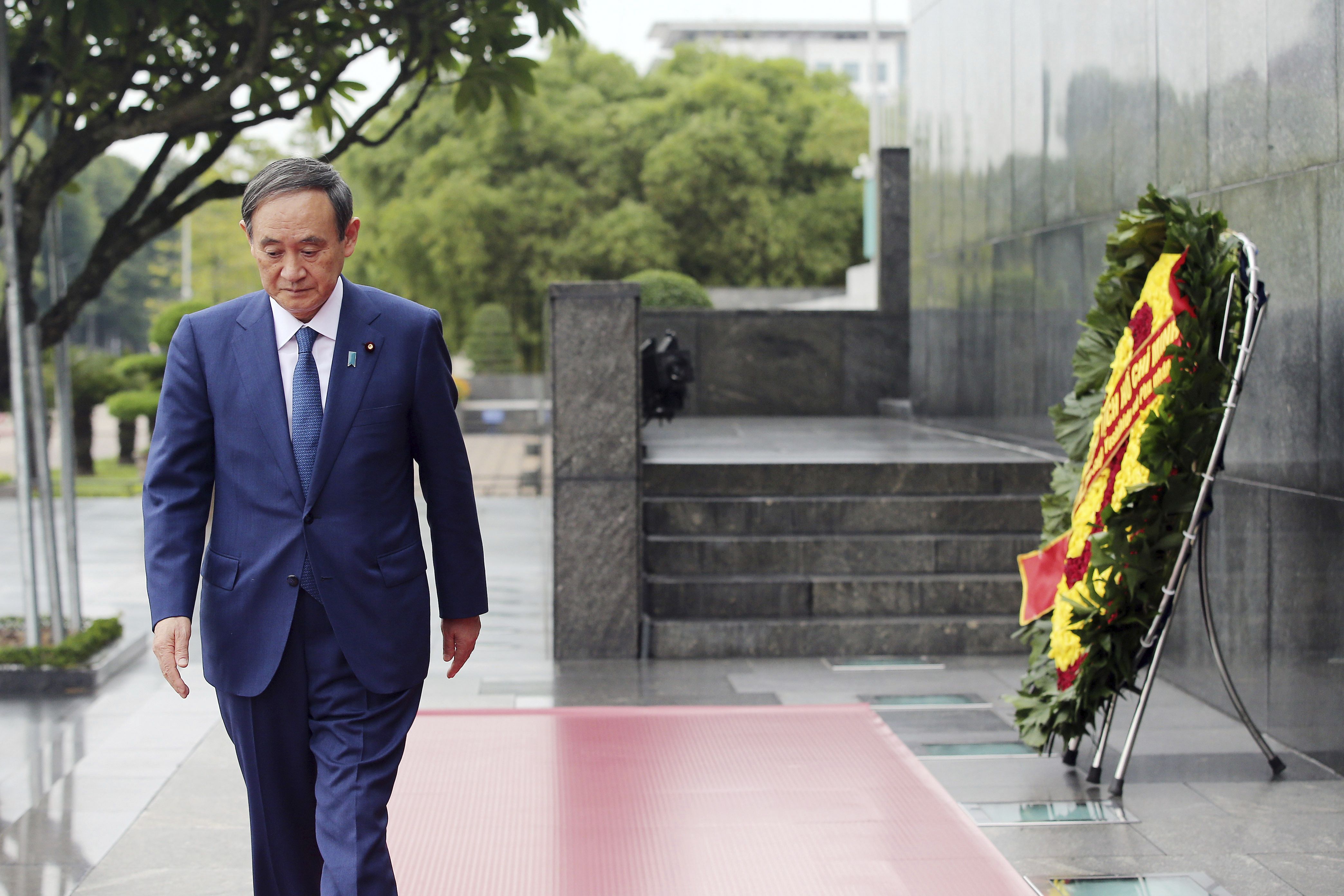 日本首相菅義偉19日在河內，向越南已故領導人胡志明獻花致敬後離去。(美聯社/達志影像)