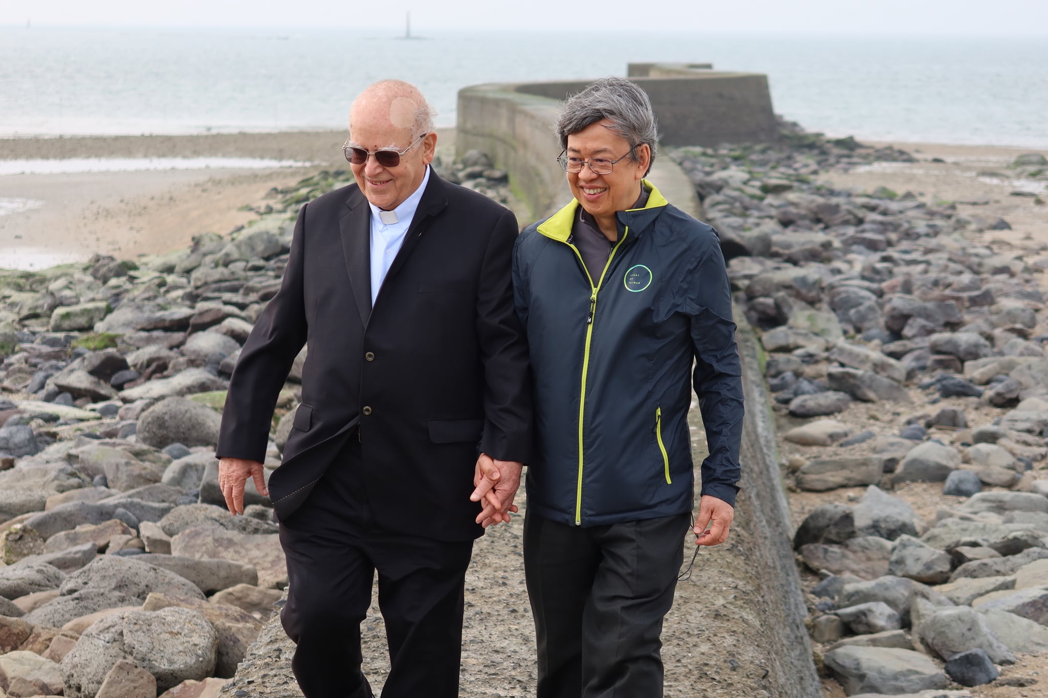 陳建仁與呂若瑟神父頂著東北季風強風，在澎湖後寮天堂路海堤上拍攝公益短片。圖:沈聰榮攝