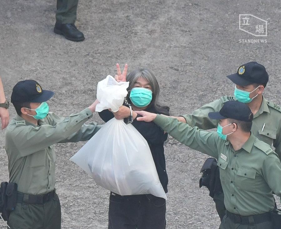 被押上庭應訊 ，香港前立法會議員梁國雄高舉 V 字手勢。(立場新聞提供)