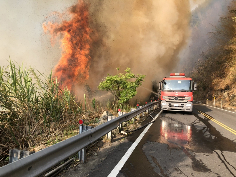 嘉義縣達邦公路18日下午發生林班地火警，一路往上燃燒，燒到台18縣阿里山公路下方，消防車在阿里山公路上灌水滅火，阿里山公路68.7K到69.2K進行機動交通管制。（嘉義縣消防局提供） (圖：中央社)