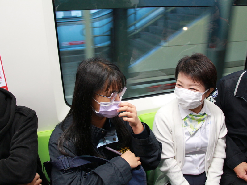 台中捷運綠線25日起恢復試營運，市長盧秀燕（右）一早搭乘首班車，得知搶搭首班車的沙鹿高工高二陳姓學生（左）生日，還為她慶生。 (圖：中央社)