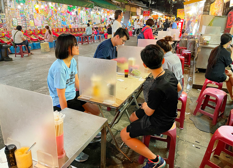 疫情指揮中心宣布，自5月11日起至6月8日，提升疫情警戒至第二級，內政部呼籲民眾務必遵守指揮中心指示，落實「個人及外出管制」、「集會活動管制」及「廣泛性營業限制」等防疫措施，並戴好口罩、勤洗手、保持社交距離，避免增加政府及醫護人員防疫工作的負擔。圖為夜市小吃攤加裝隔板。 (圖：中央社)