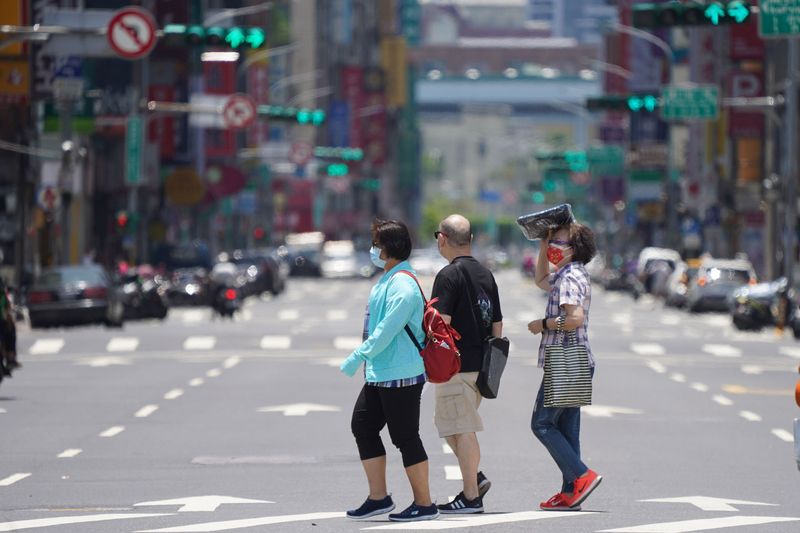 中央氣象局指出，今天(4日)各地天氣大多仍為多雲到晴，但午後雷陣雨範圍將會擴大。圖為民眾以物品遮擋豔陽，行走在北市街頭。 (圖：中央社)