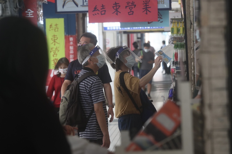 疫情警戒降級讓商家稍稍恢復生計，無薪假人數下滑至5.5萬人，不過家數仍續創歷史新高。圖為民眾在一家零售店挑選商品。 (圖：中央社)