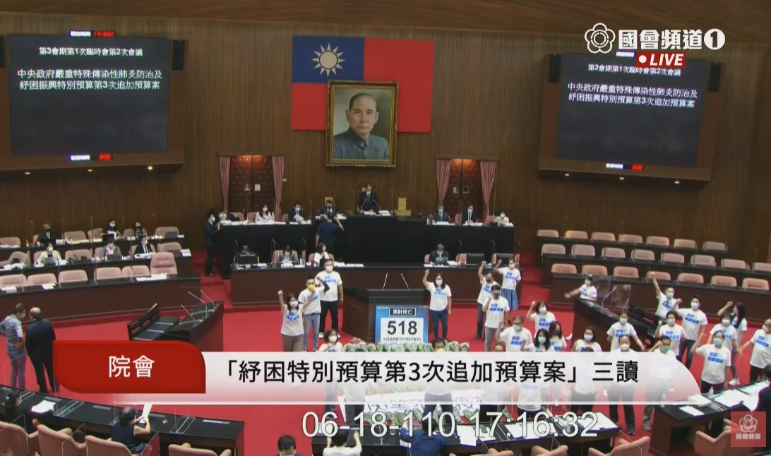立法院臨時會18日三讀通過「紓困4.0特別預算案」後，國民黨團在議場內擺上白色菊花，為因染疫而身亡的500多位國民哀悼致意，並轉向總統府前抗議，揚言要追究政府的責任。(圖擷自國會頻道)