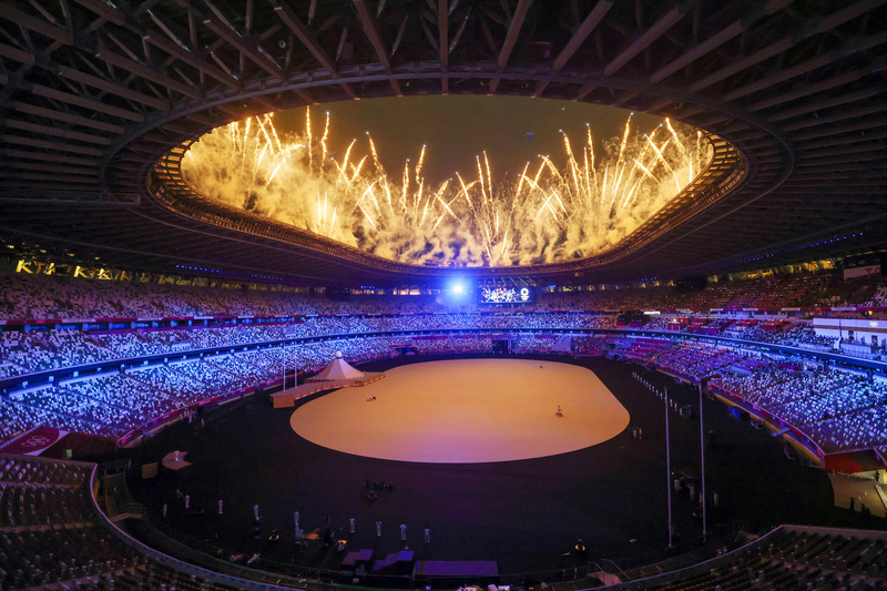 東京奧運23日晚間在日本新宿國立競技場舉行開幕式，受疫情影響本屆典禮並未開放觀眾進入場內，但現場表演仍照常舉行，璀璨煙火自場館高處噴發，點亮夜空。 (圖：中央社)