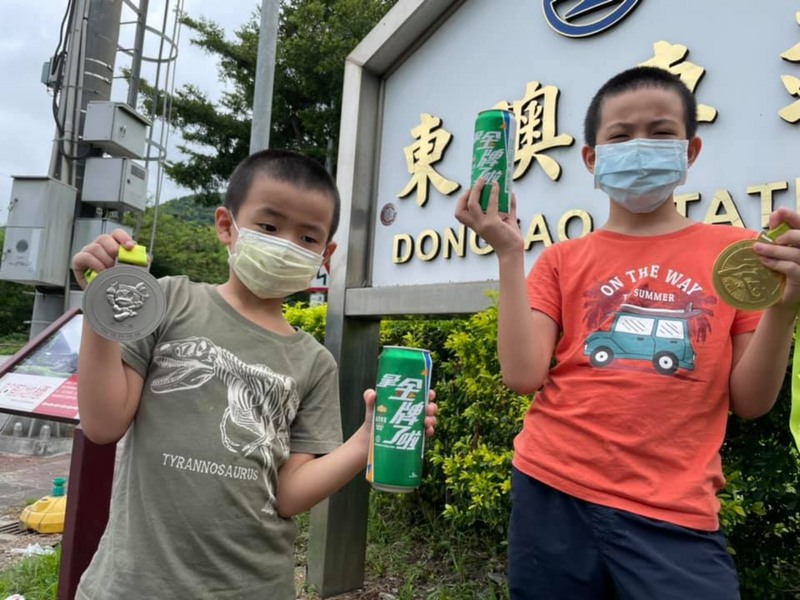 不少民眾近日搭上東京奧運熱潮，前往位於宜蘭縣南澳鄉東岳村的東澳車站，一手持獎牌，另一手拿著印有「拿金牌了啦」啤酒遮住東澳車站「澳」字的水字旁，與東澳車站合影，發揮創意為中華隊加油。（鄒姓民眾提供） (圖：中央社)