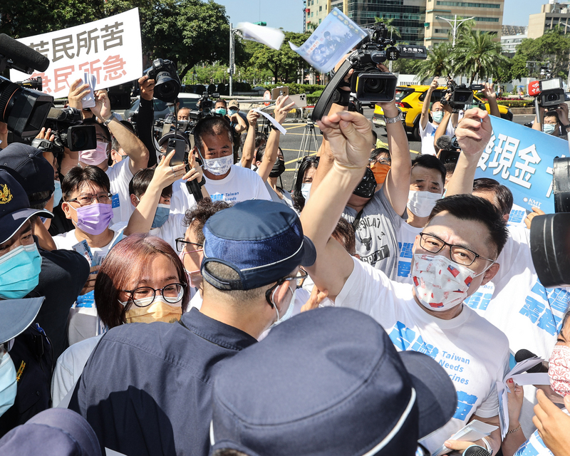 國民黨16日上午在行政院前舉行「紓困發現金」記者會，國民黨主席江啟臣（前右）等人高呼口號、灑玩具紙鈔表達訴求，一度要強行進入行政院，與警方發生推擠。 (圖：中央社)