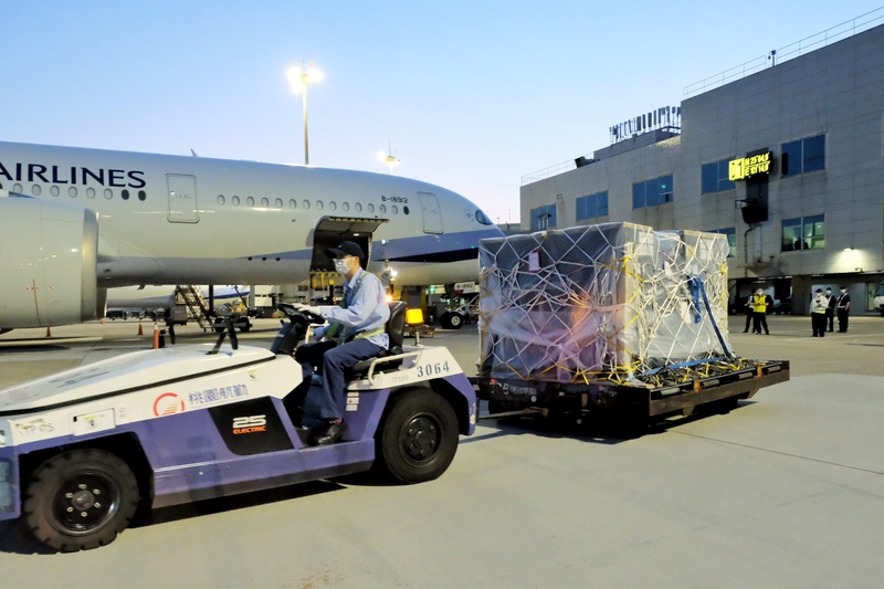 首批客製化標籤輝瑞BNT疫苗完成通關、消毒作業後，經拖車送往貨物碼頭裝入冷鏈貨車，載往指定冷儲物流中心存放，進行後續檢驗封緘作業。 (圖：中央社)