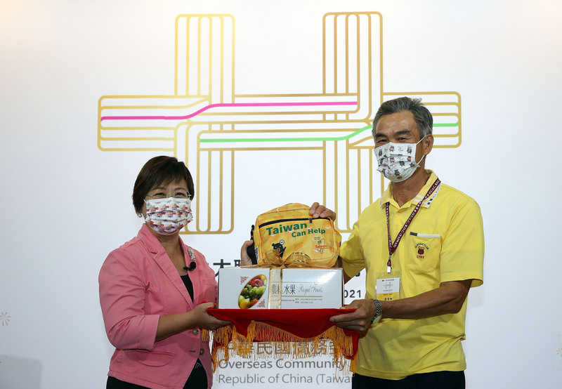 僑委會副委員長徐佳青（左）5日表示，110年雖受疫情阻礙，仍有近千位僑胞回台參加國慶大典；為鼓勵僑胞多旅遊、消費，除了可以領五倍券外，還有回國僑胞旅遊補助金新台幣3000元，盼大家多認識台灣之美。圖為徐佳青致贈紀念品給首位報到的僑胞、在澳大利亞經營農場的廖貴興（右）。 (圖：中央社)