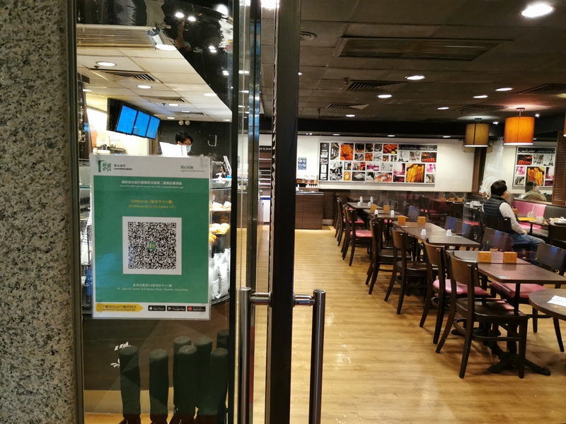 香港COVID-19疫情嚴峻，自2月24日起，港人接種了疫苗後才能進入食店等場所；圖左是食店張貼的「安心出行」編碼，市民用手機掃描，即可顯示疫苗接種紀錄。 (圖：中央社)