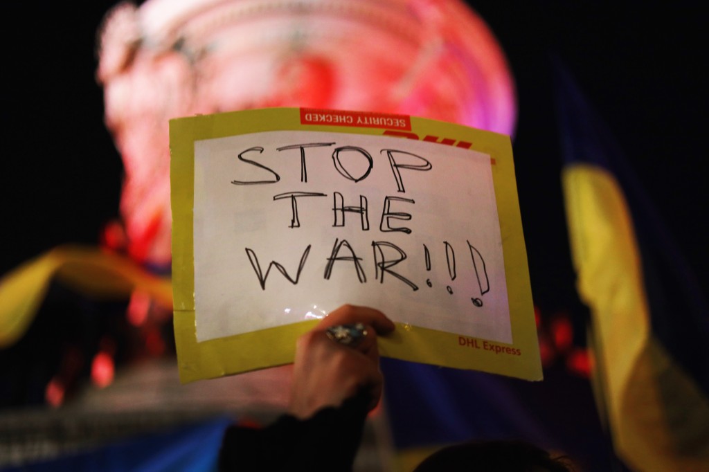 民眾手持標語抗議俄羅斯對烏克蘭開戰。(AFP)