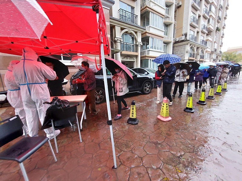圖為上海社區居民在雨中排隊做檢測。 (圖：中央社)