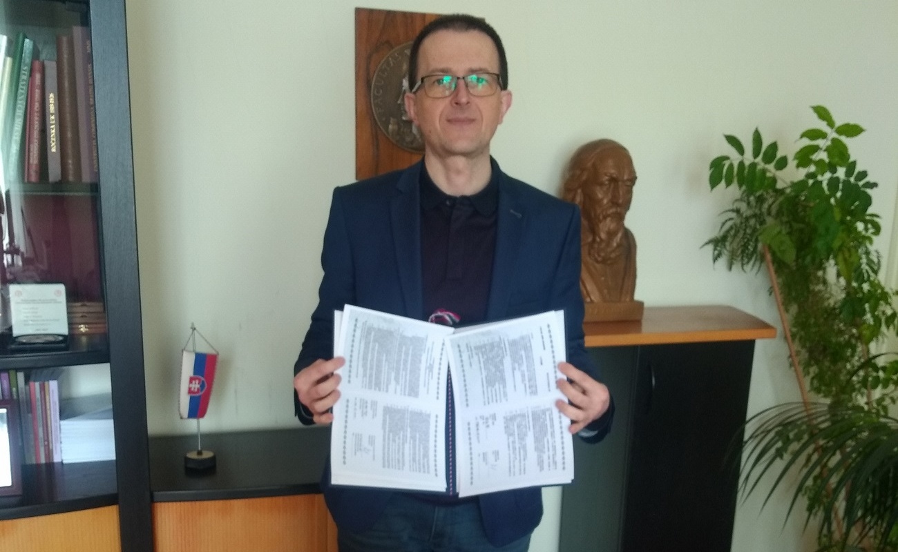 考麥紐斯大學藝術學院院長Marián Zouhar拿起中、英文版「台灣漢學資源中心」合作協議。(國家圖書館提供)