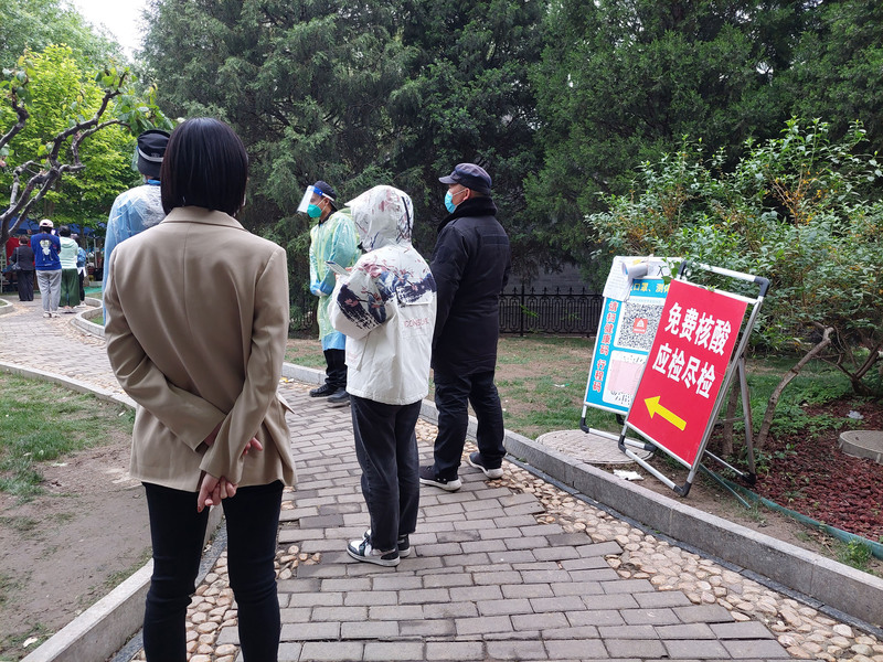圖為27日北京東城區一處設在小公園的核酸檢測點，工作人員會提醒排隊者注意間距，避免交互感染。(圖：中央社)
