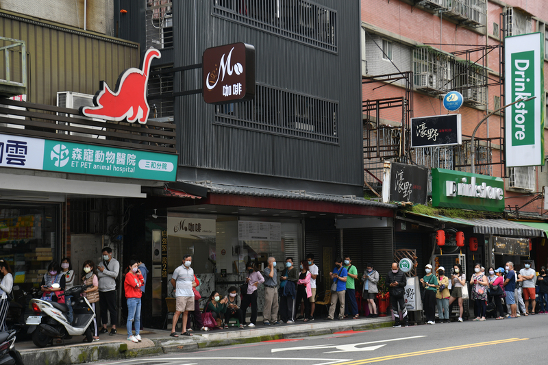 圖為5日上午新北市三重區一間藥局外，民眾於人行道上依序排隊等待實名制快篩試劑開賣。 (圖：中央社)