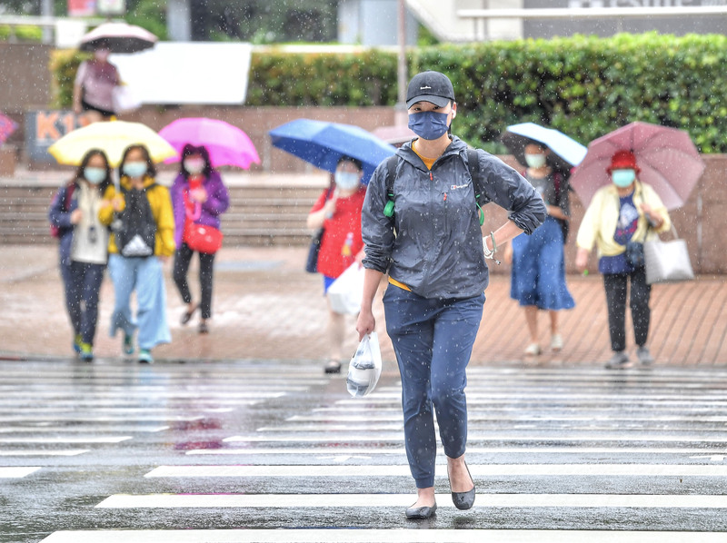 中央氣象局指出，今天(15日)仍受鋒面影響，各地還是屬於容易下雨的天氣。圖為台北市區飄雨，台北車站前民眾戴著帽子、撐傘過街。 (圖：中央社)