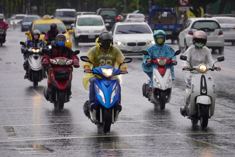 受到滯留鋒面影響，各地降下大雨，中央氣象局27日也持續發布大雨及豪雨特報。圖為高雄市苓雅區民眾上午騎車穿上雨衣。 (圖：中央社)