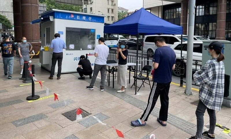 圖為上海徐匯區的一處採樣站，民眾正在排隊等待「開門」。 (圖：中央社)
