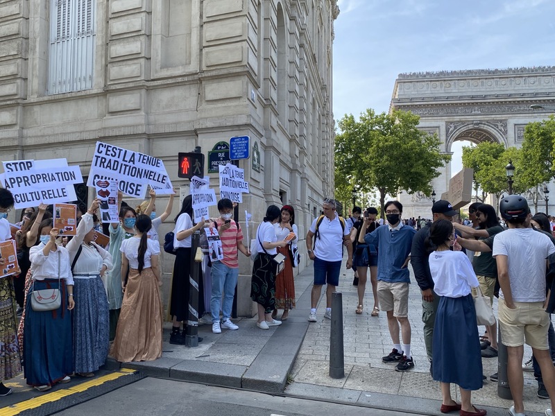23日抗議迪奧文化挪用的現場也出現10多名中國籍反示威人士，其中3人手舉標語，諷刺抗議者從不為更重要的人權發聲，卻因一款裙子上街。 (圖：中央社)
