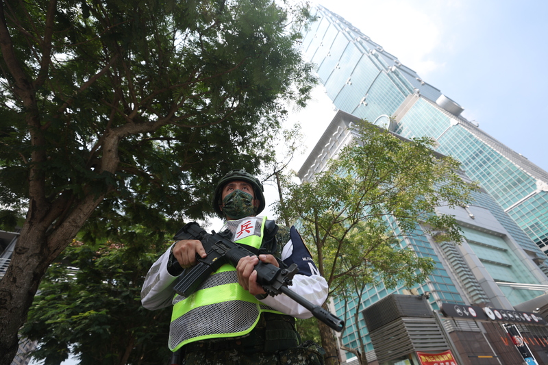 圖為萬安演習警報施放期間實施人員離車疏散，信義商圈在警報發布後，憲兵引導行人至捷運站避難，並有憲兵荷槍實彈在台北101大樓周邊警戒。(資料照片/CNA)