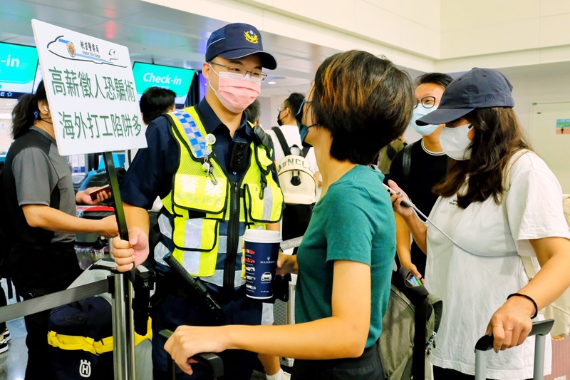 鑒於近期民眾至柬埔寨打工遭詐、被囚案頻傳，警方在桃園機場持手牌宣導，主動關懷詢問，了解出境的目的動機。  (圖：中央社)