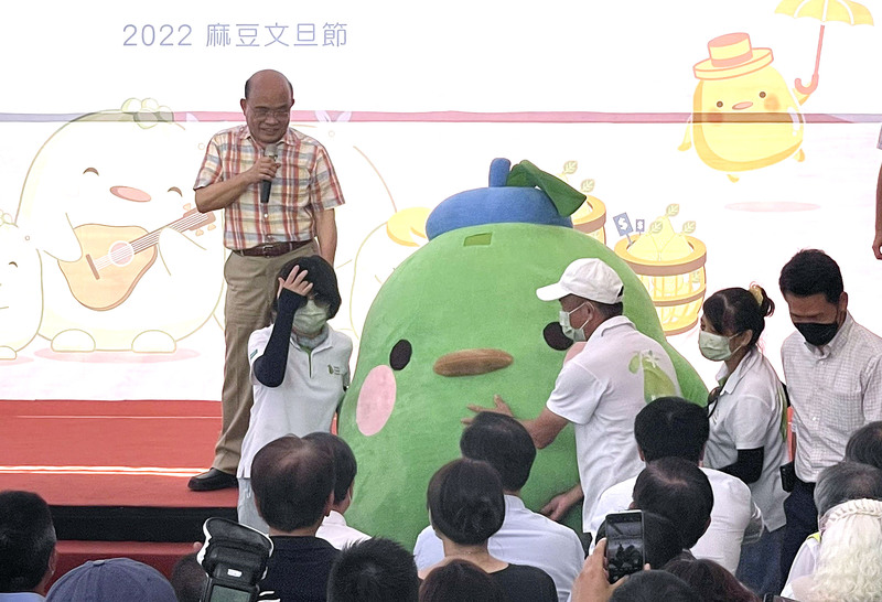 行政院長蘇貞昌27日下午到台南市麻豆區行銷當地特產文旦，不過因天氣炎熱、高溫難耐，蘇貞昌也貼心請現場工作人員先脫下文旦人偶裝，以防熱傷害上身。(圖：中央社)