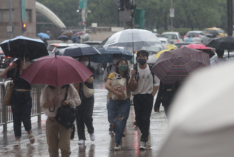 中央氣象局更新豪雨特報，受到颱風梅花外圍環流影響，新北市及桃園市山區有局部大雨或豪雨，台北也有局部大雨發生的機率。圖為台北車站周邊民眾撐傘逛街。 (資料照片/中央社)
