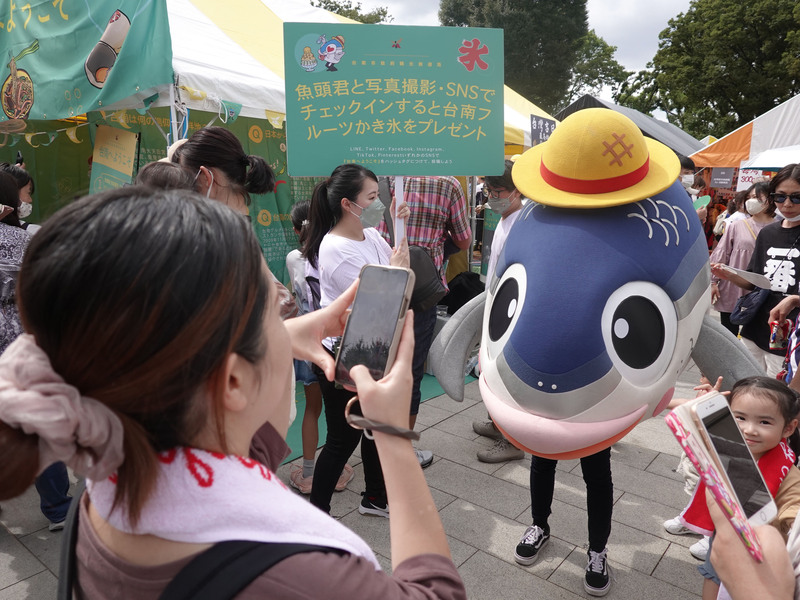 中華文化總會主辦2022 TAIWAN PLUS台灣吉日生活節17日在東京登場，台南設攤推出結合飲食、文化與觀光元素的趣味性集客活動，民眾爭相與吉祥物魚頭君拍照。 (圖：中央社)