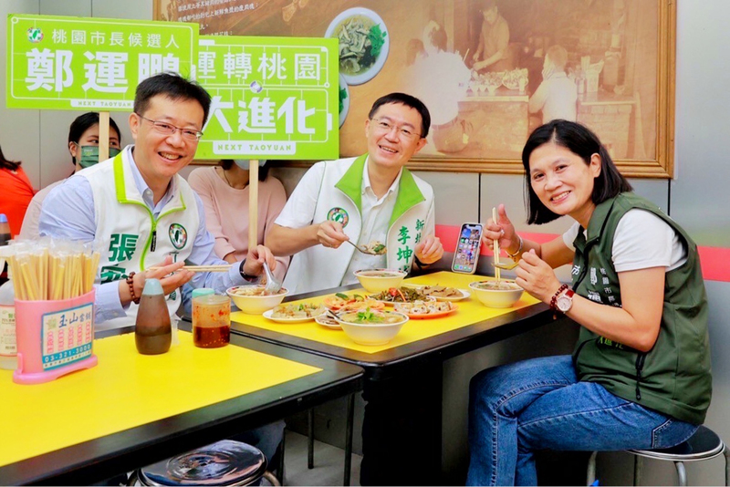 民進黨桃園市長參選人鄭運鵬因確診居家隔離，25日由新北市立委張宏陸（左）、議員李坤城（中）擔任鄭運鵬分身，在桃園市議員郭麗華（右）陪同下到蘆竹區南崁市場掃街拜票，並品嚐在地小吃。（鄭運鵬競辦提供）(圖：中央社)