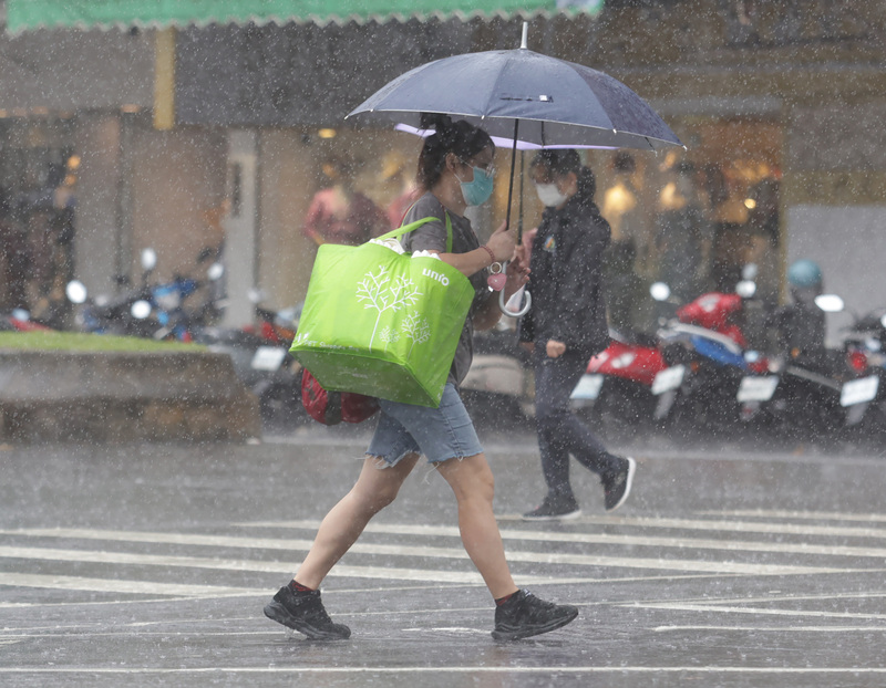東北季風持續影響，中央氣象局表示，今日宜蘭與新北山區仍須留意豪雨，北部地區平地不定時會有降雨。圖為走在台北市信義區街頭的民眾撐傘遮擋雨勢。 (圖：中央社)