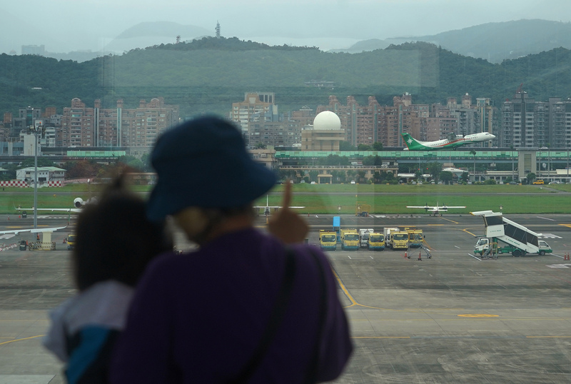 台灣13日將解封邊境，旅遊業商機預期將逐日回升。圖為家長帶孩子在台北松山機場觀看飛機起降。 (圖：中央社)
