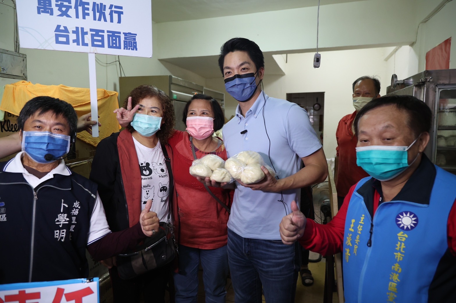 國民黨台北市長參選人蔣萬安(右二)12日到成德市場掃街，有店家熱情送上包子，祝他「包中」。(蔣萬安競辦提供)