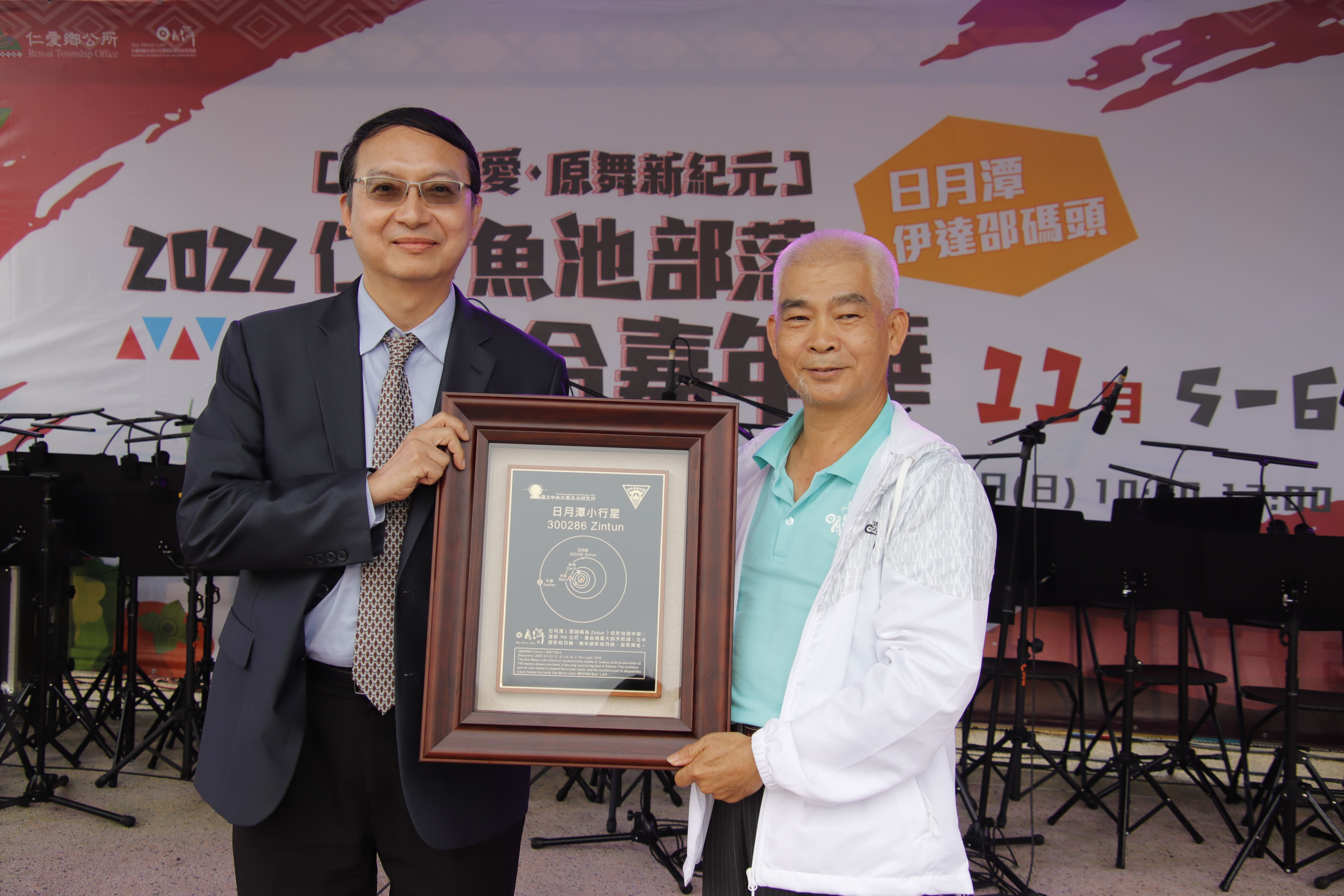 中央大學將編號第300286號小行星以日月潭的邵語Zintun命名，5日在仁愛魚池部落聯合嘉年華中，由中央大學主秘周立德（左）代表頒贈小行星銘牌，日月潭國家風景區管理處長簡慶發（右）代表接受。(中央大學提供)