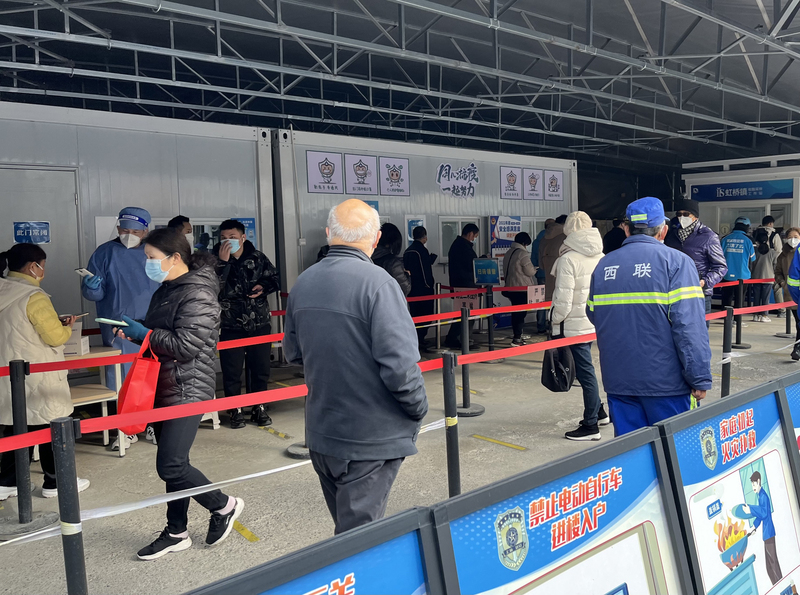 中國鬆綁COVID-19防疫措施，提倡「非必要不核酸檢測」；由於工作需求或是單位要求，部分民眾仍然必須執行核酸檢測。圖為上海市某區核酸檢測採樣站13日情形，民眾排隊等待採樣。 (圖：中央社)