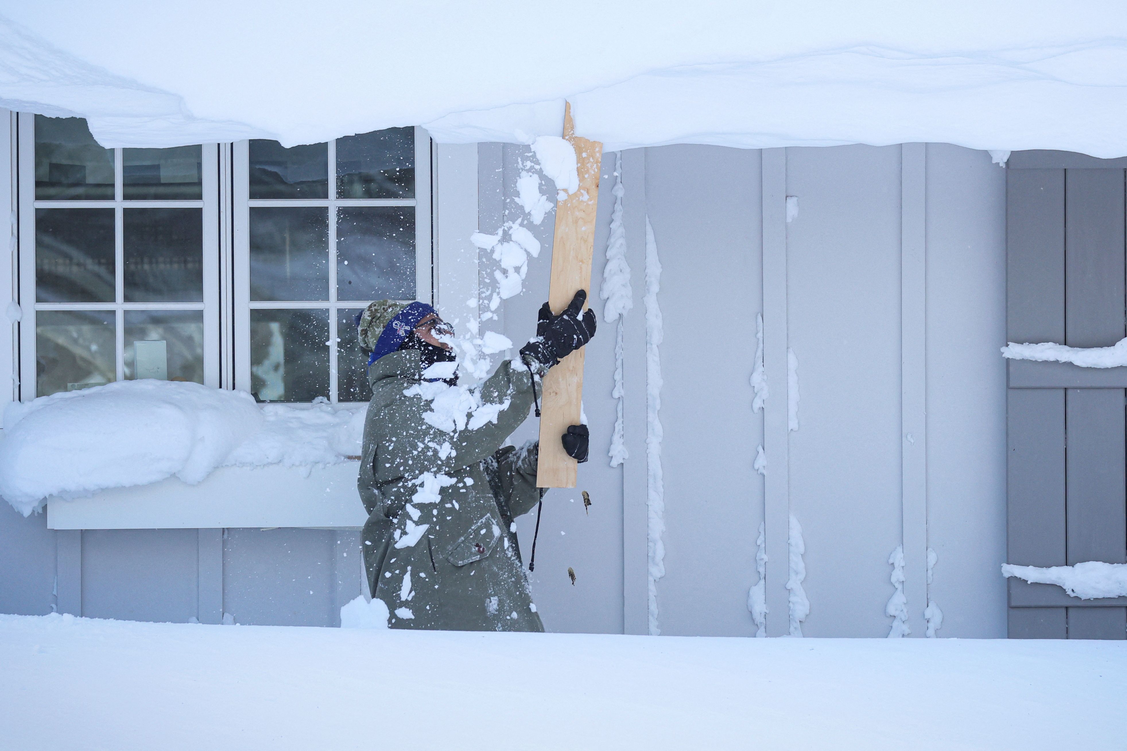 紐約水牛城遭受暴風雪襲擊，圖為一位民眾25日剷除住宅屋頂上的積雪．(路透社/達志影像)