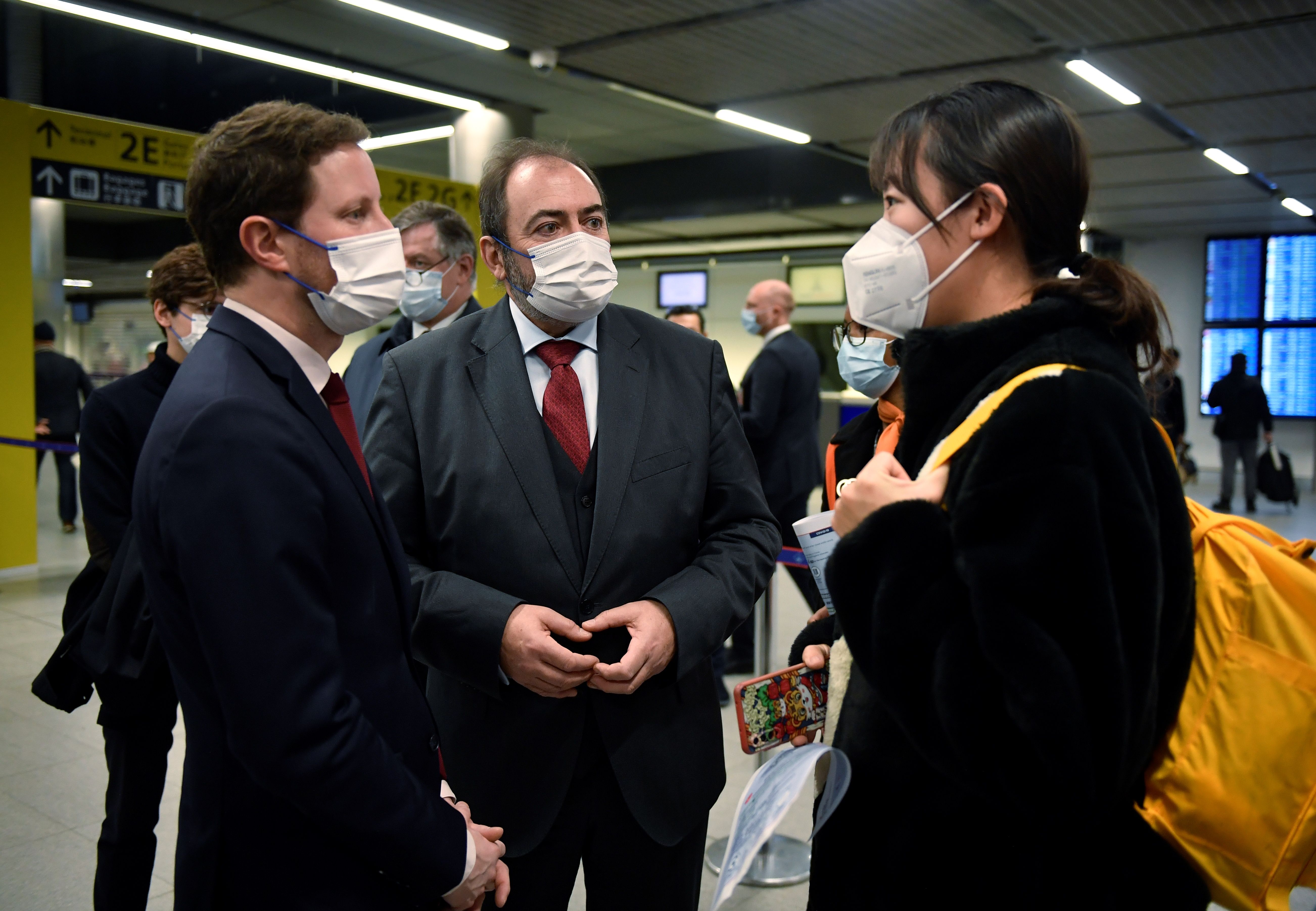法國衛生部長布勞恩(François Braun)(中) 和交通部長波恩(Clement Beaune)(左)1日巡視巴黎戴高樂機場，並與一名中國遊客交談。(AFP)