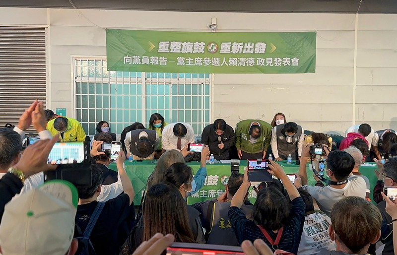 民進黨主席補選候選人賴清德（後中黑衣持麥克風者）14日晚間回台南娘家「向黨員報告」，面對批判聲浪，賴清德當場與台南市長黃偉哲及黨籍立委一同鞠躬道歉。 (圖：中央社)