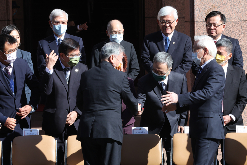 行政院30日上午舉行臨時院會，行政院長蘇貞昌正式率內閣總辭，全員循慣例到行政院中央大樓前廣場拍攝「畢業照」，現任行政院副院長沈榮津（前排中，背對者）與衛福部長薛瑞元（2排右2）等握手致意。(圖：中央社)