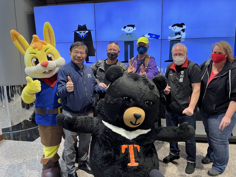交通部長王國材（左）25日視察桃園國際機場，與外國旅客互動，並發放桃園機場開航44週年紀念巧克力。 (圖：中央社)