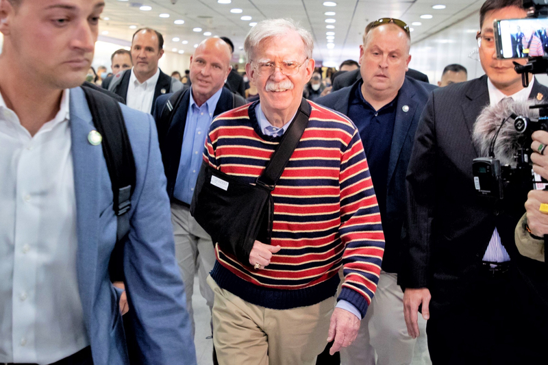 美國前白宮國安顧問波頓(John Bolton)(前中)26日中午抵達桃園國際機場，右手戴著手肘關節固定護具，親切向在場守候記者致意，但未停留發表談話。 (圖：中央社)