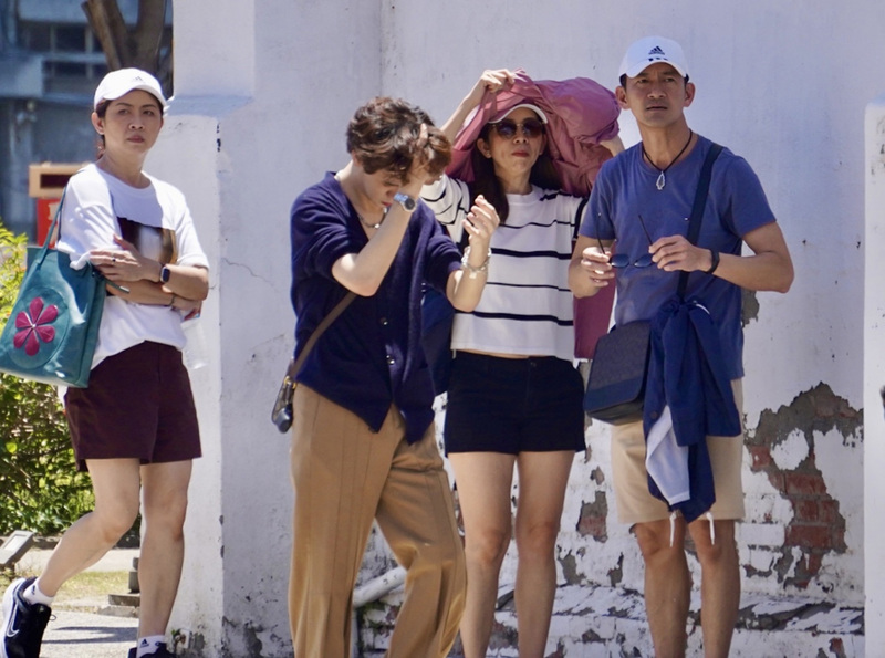 中央氣象局指出，5日南高屏地區留意攝氏38度以上高溫 。圖為鹽埕區出遊民眾拿起薄外套遮陽。(圖：中央社)