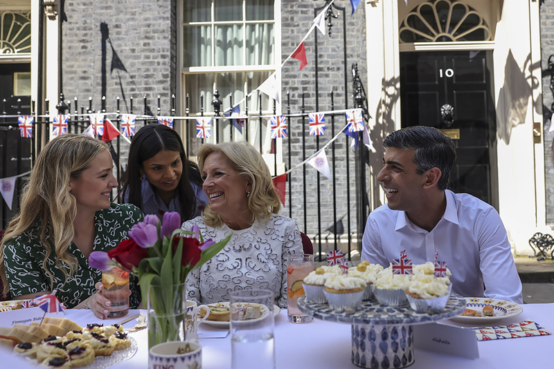 英國首相府7日舉行加冕主題街頭午餐派對，除了烏克蘭難民和英國各界熱心公益人士，美國第一夫人吉兒．拜登（右2）也應邀出席，與首相蘇納克（右1）和妻子阿克莎塔．莫西（左2）同桌。（英國首相府提供）(圖：中央社)