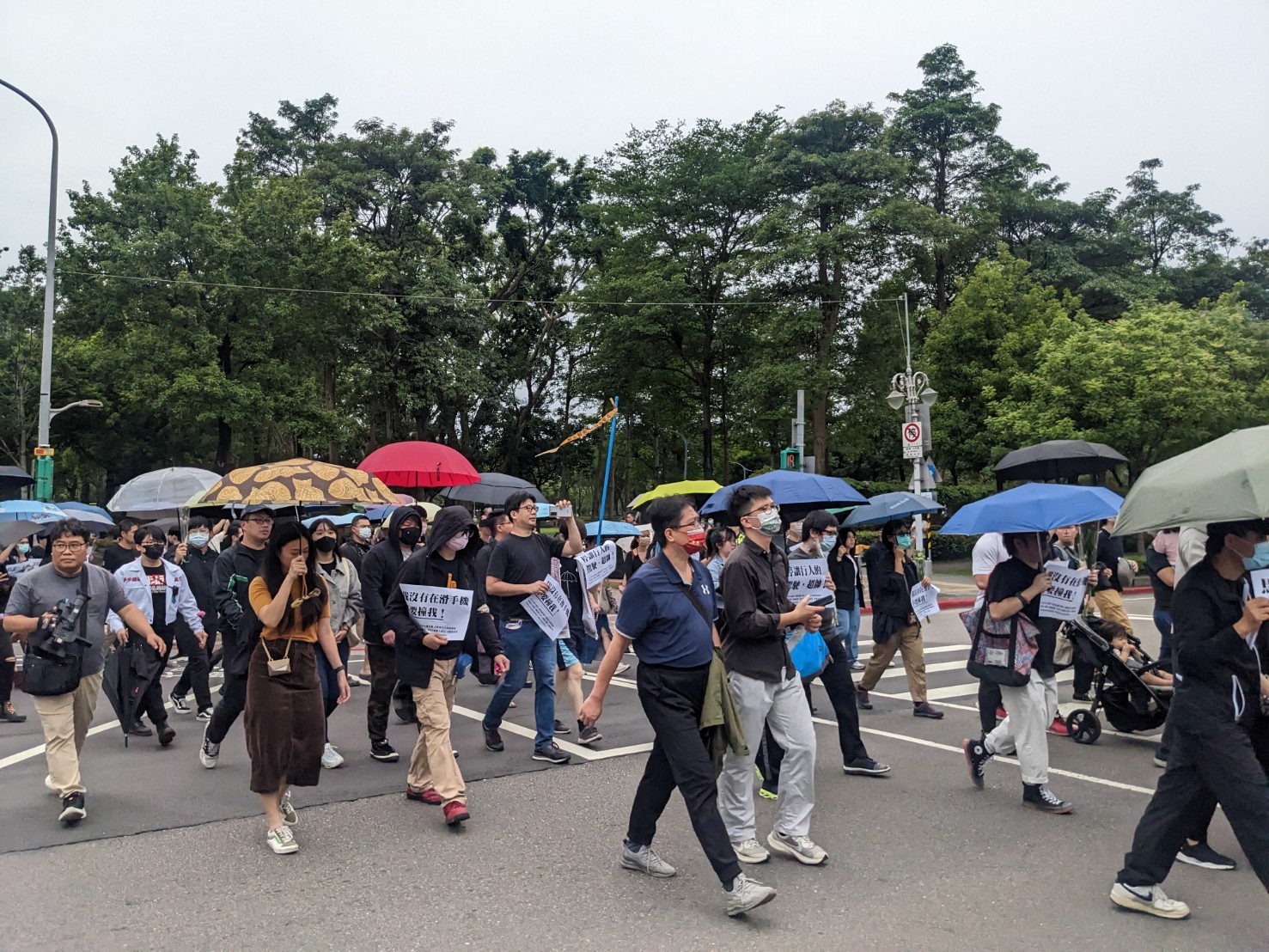 「行人安全大富翁」快閃活動14日早上登場，台北市建國南路信義路口湧現人潮，有的民眾手舉標語表達訴求，有的民眾則手持雨傘，象徵撐起行人的保護傘。(陳念宜 攝)