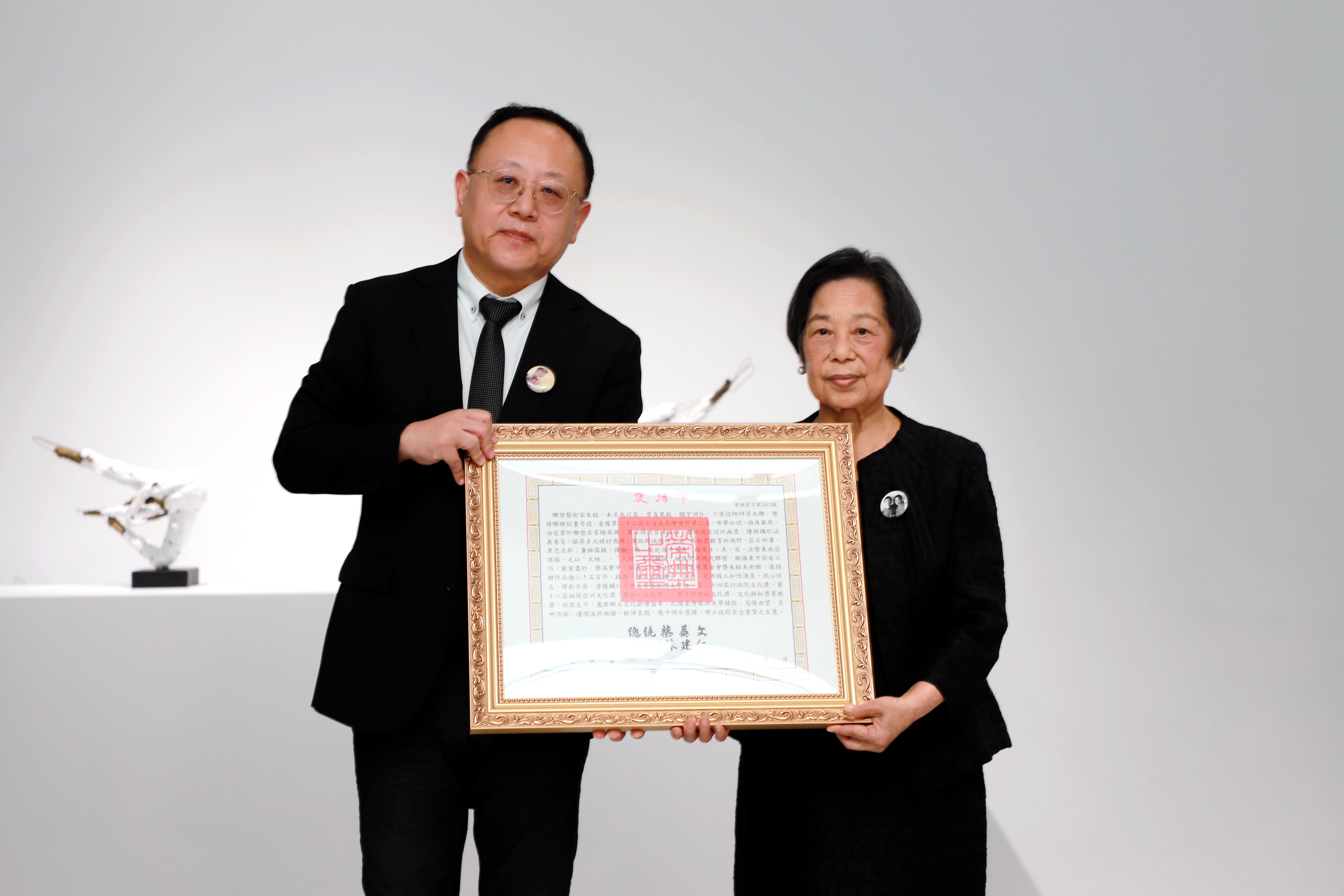 現代雕塑大師朱銘辭世，為表彰其對臺灣藝術發展的重要貢獻，文化部長史哲(左)今（18）日赴朱銘美術館代表總統頒贈褒揚令，由朱銘夫人朱陳富美女士(右)代表受贈。(文化部提供)