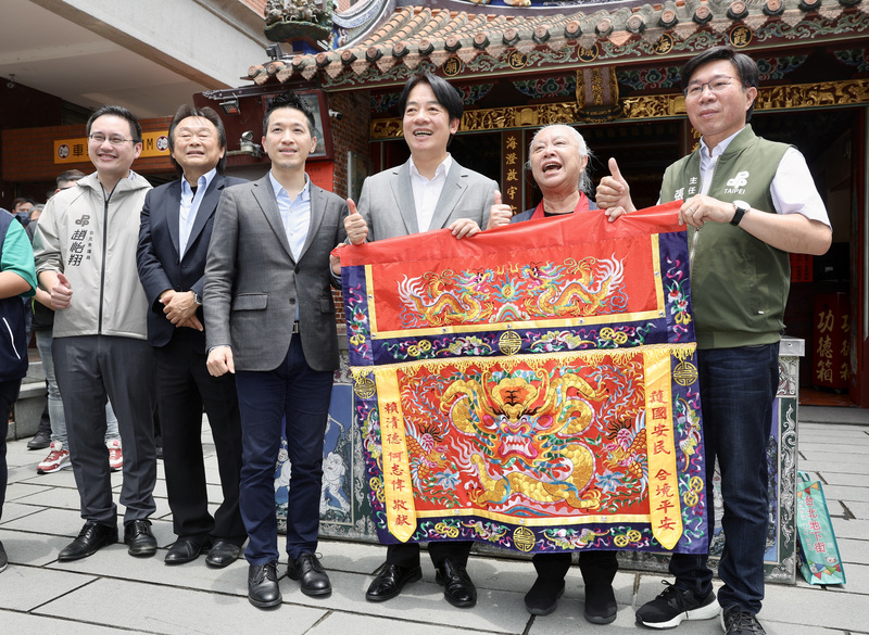 副總統賴清德（右3）25日前往台北霞海城隍廟參香，並與民進黨立委何志偉（左3）等人致贈廟方桌圍。 (圖：中央社)