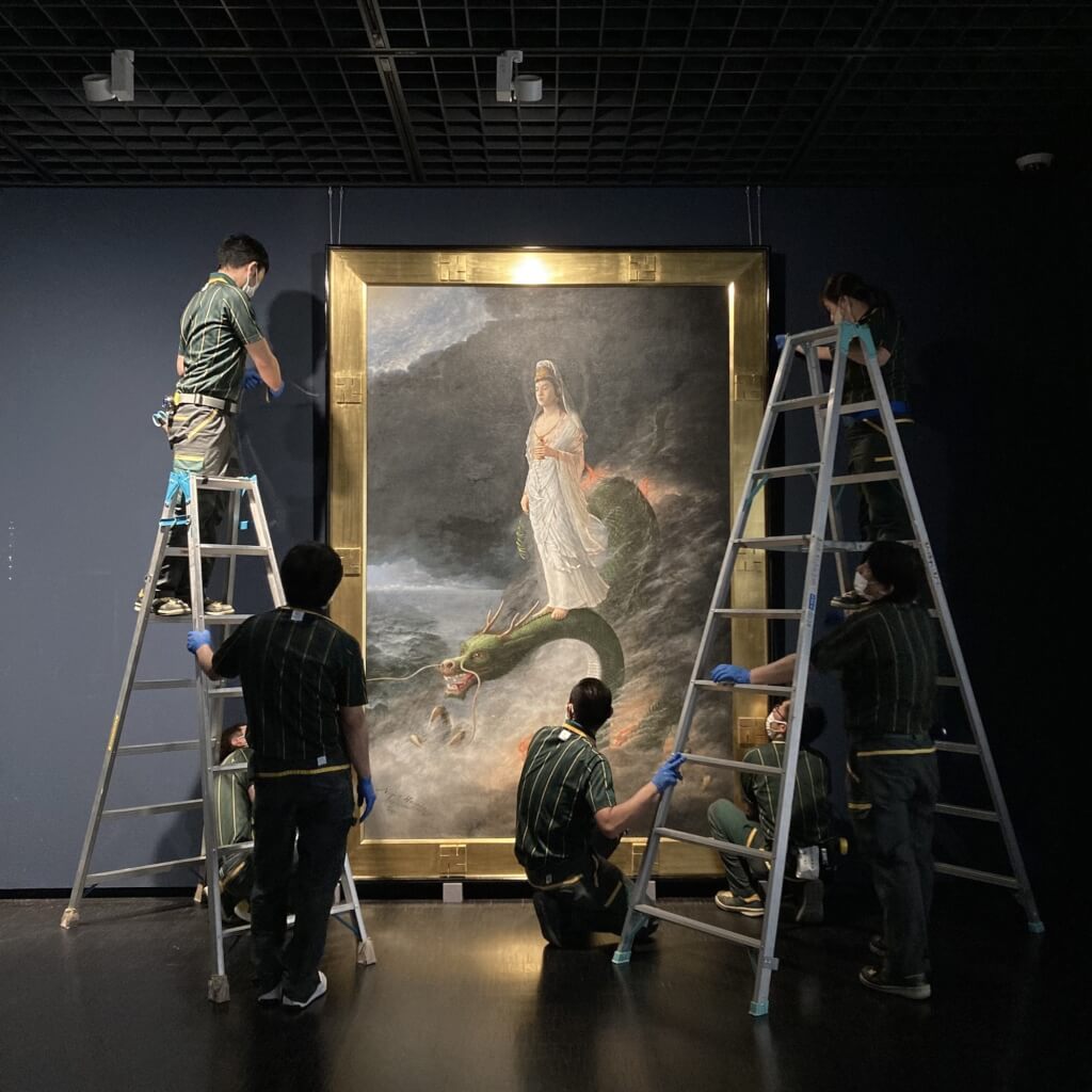 日本東京國立近代美術館日前於臉書（Facebook）粉絲專頁貼出最新展覽布展照，工作人員圍繞的中心是日本畫家原田直次郎的畫作「騎龍觀音像」。（日本東京國立近代美術館臉書）