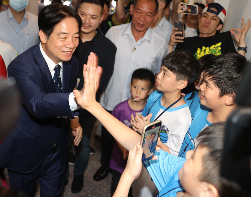 「大手牽小手 益童GIVE ME FIVE 聯歡童樂會」11日在總統府南、北苑熱鬧舉行，副總統賴清德（前左）到場參觀攤位，和與會大小朋友擊掌致意。(圖：中央社)