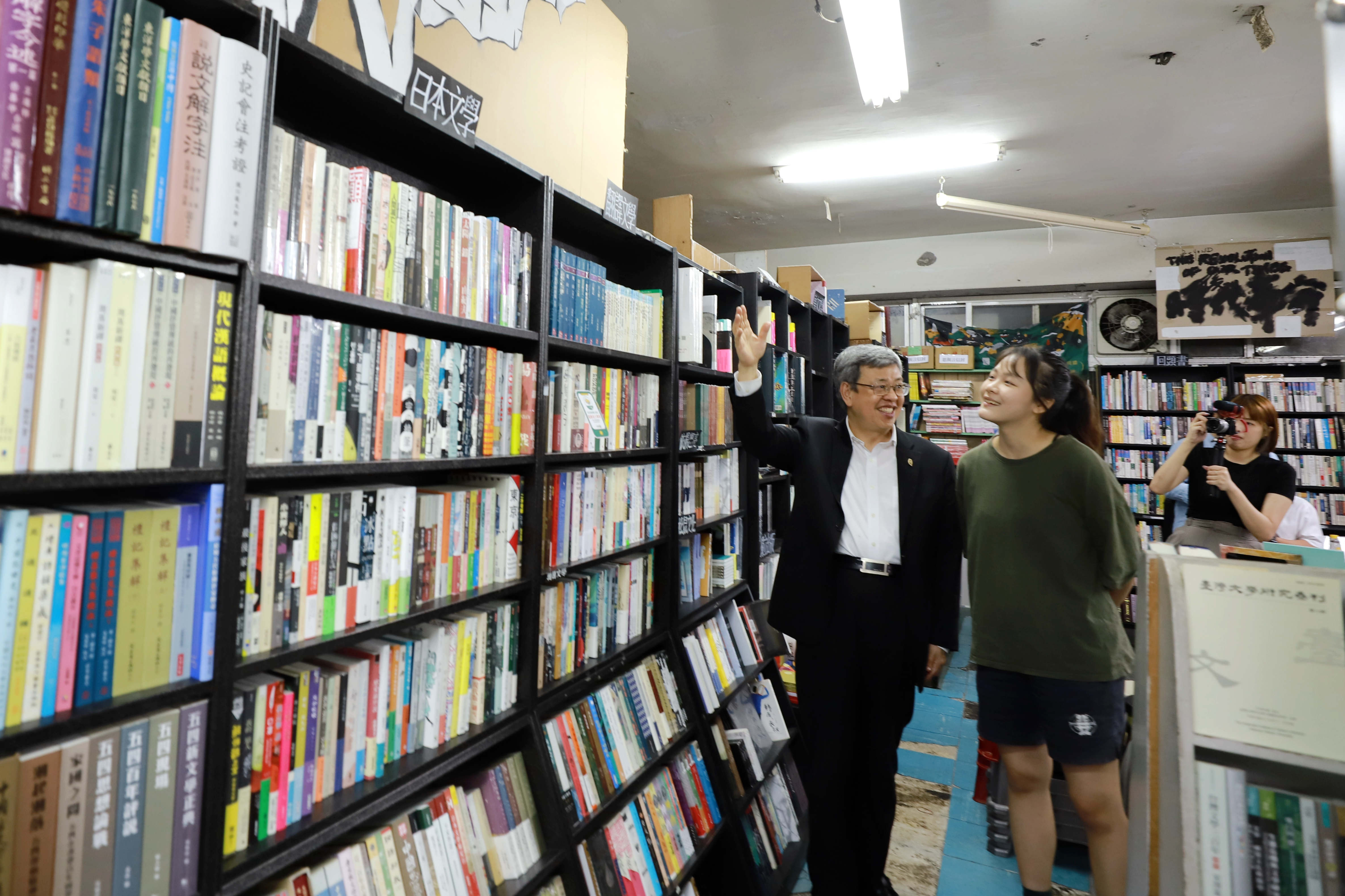 行政院長陳建仁(左)與YouTuber李怡蓁(右)細細分享唐山書店的陳設及選書偏好。(文化部提供)